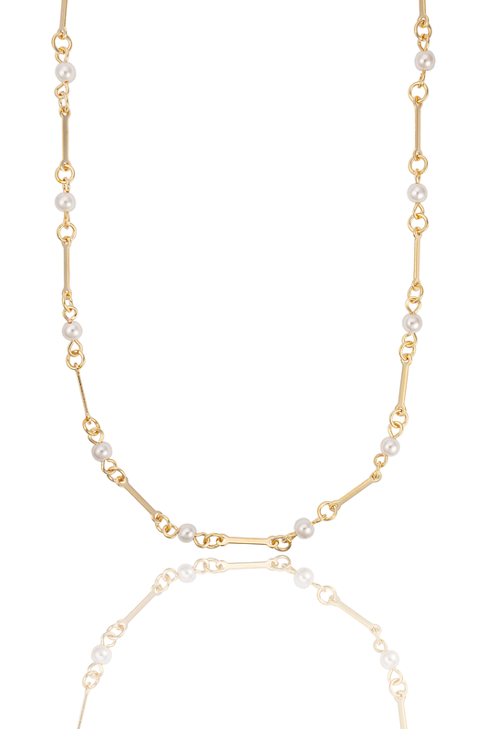 A delicate gold chain necklace interspersed with small white pearls is displayed against a clean white background, casting a soft reflection below.