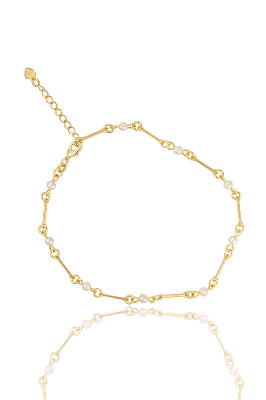 A delicate gold chain bracelet features alternating metallic bars and small white pearls against a clean white background.