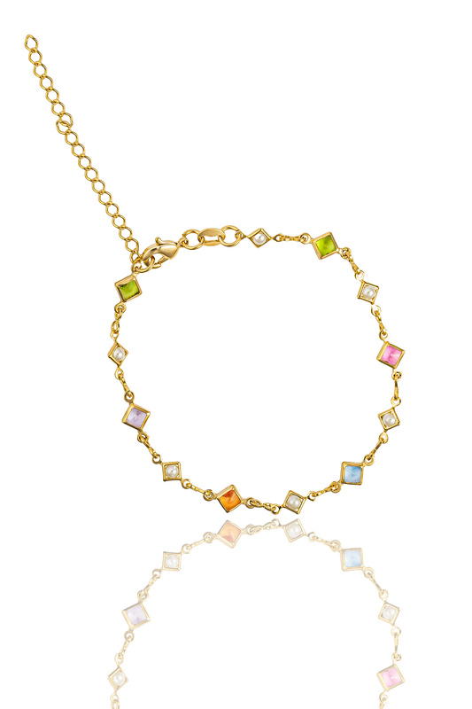 A delicate gold chain bracelet features alternating multicolored square gemstones and white pearls against a white background.