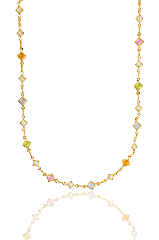 A delicate gold chain necklace sparkles with alternating colorful square gemstones and small pearls against a clean white background.
