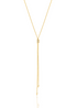 A delicate gold lariat necklace features a sliding cylinder bead and dangling chains ending in small spheres against a white background.