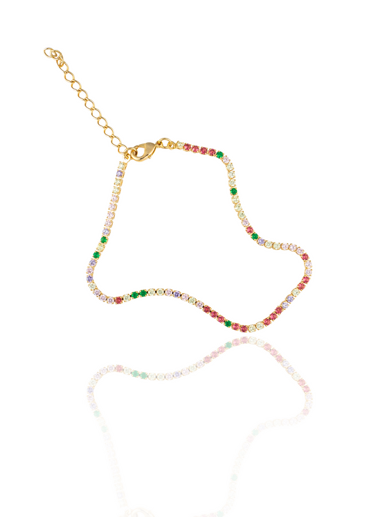 A delicate gold tennis bracelet sparkles with colorful cubic zirconia stones in shades of pink, green, and white against a clean white background.