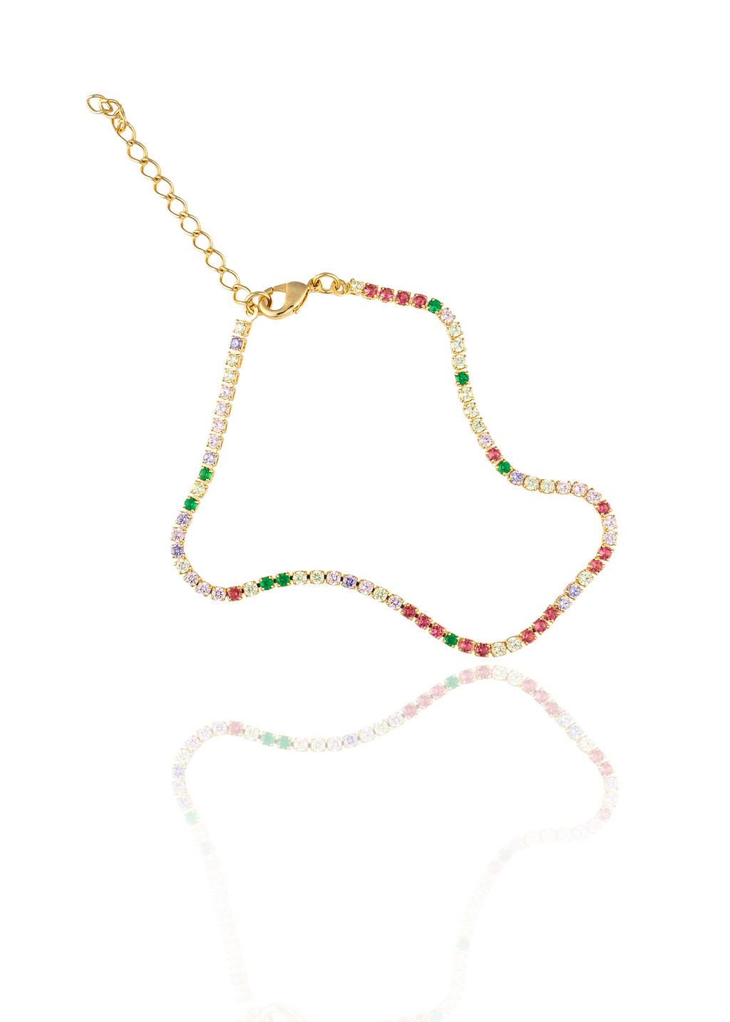 A gold tennis bracelet featuring colorful multicolored gemstones lies on a reflective white surface against a clean background.