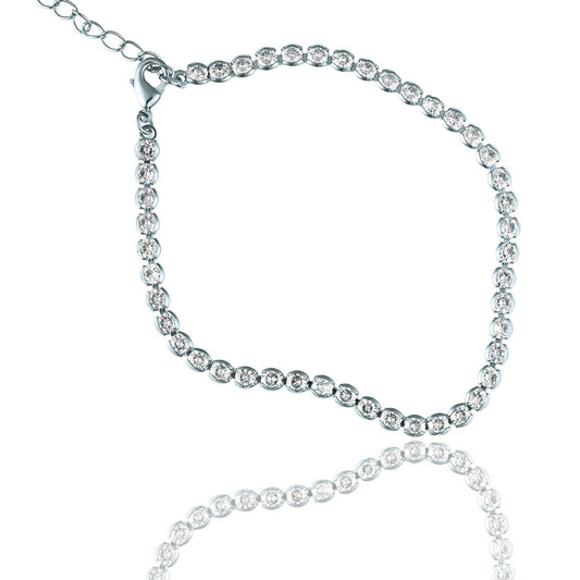 A sparkling silver tennis bracelet with a clasp and extension chain rests against a white background, casting a gentle reflection below.