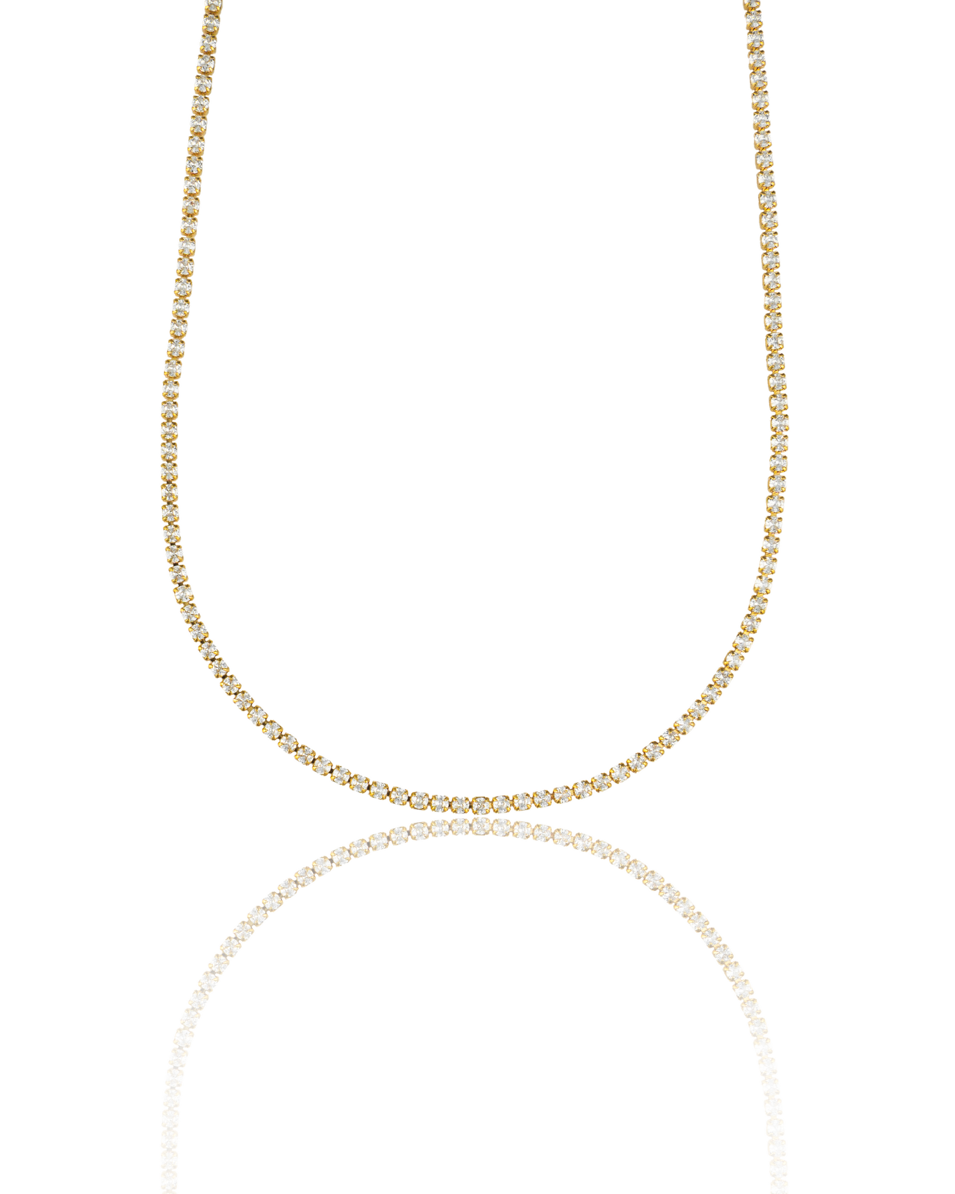 A glittering gold diamond tennis necklace sparkles against a clean white background, reflecting softly on a polished surface.
