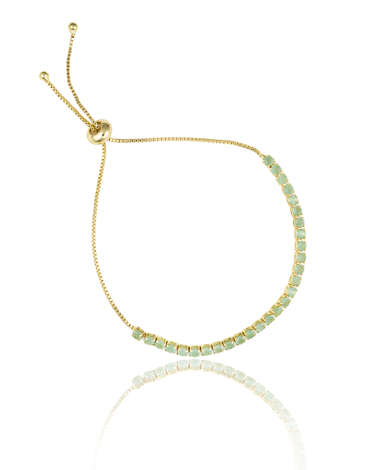 A delicate gold bolo tennis bracelet features a curved line of small, round green stones and an adjustable sliding closure.