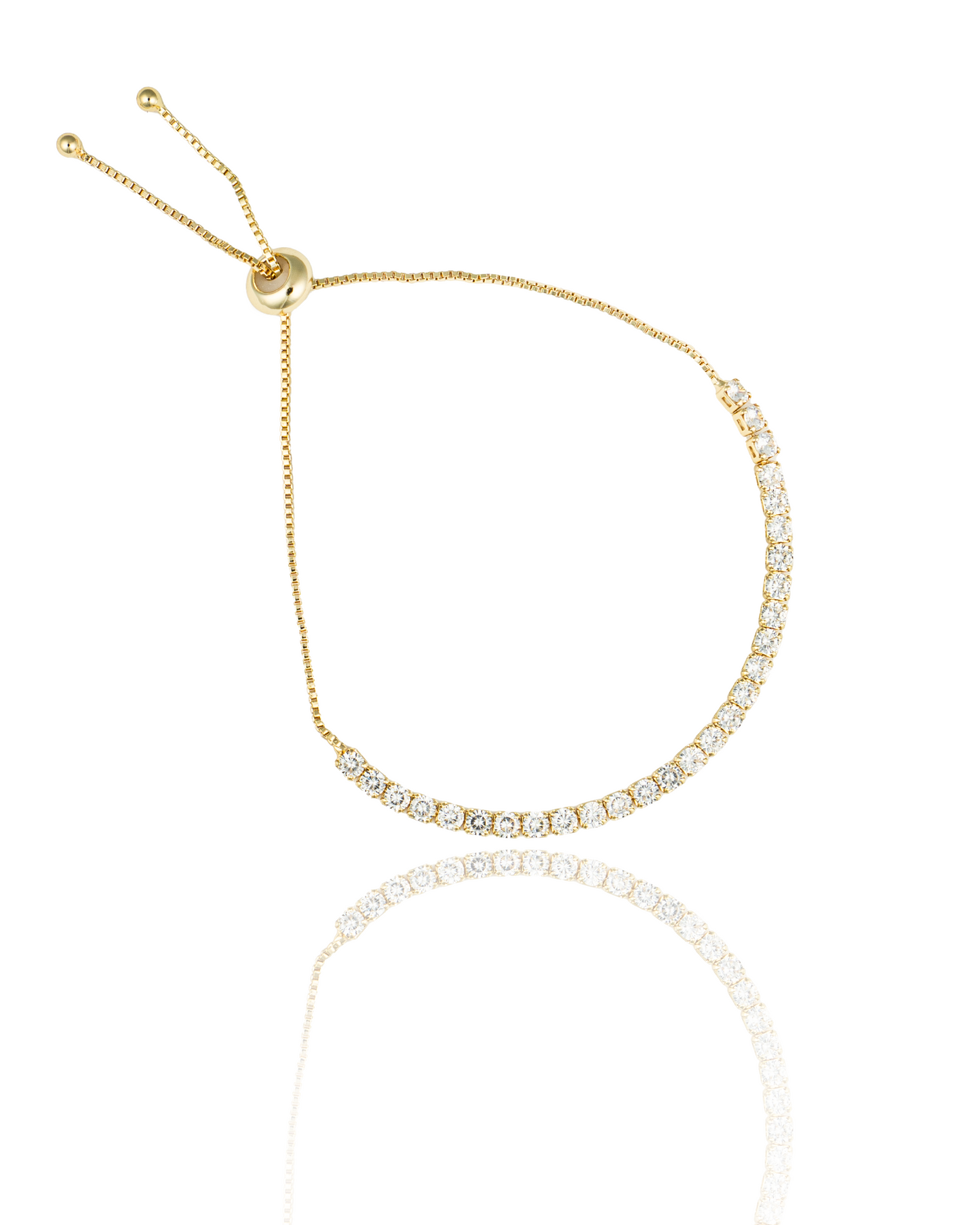 A delicate gold bolo tennis bracelet sparkles with cubic zirconia stones against a white background.