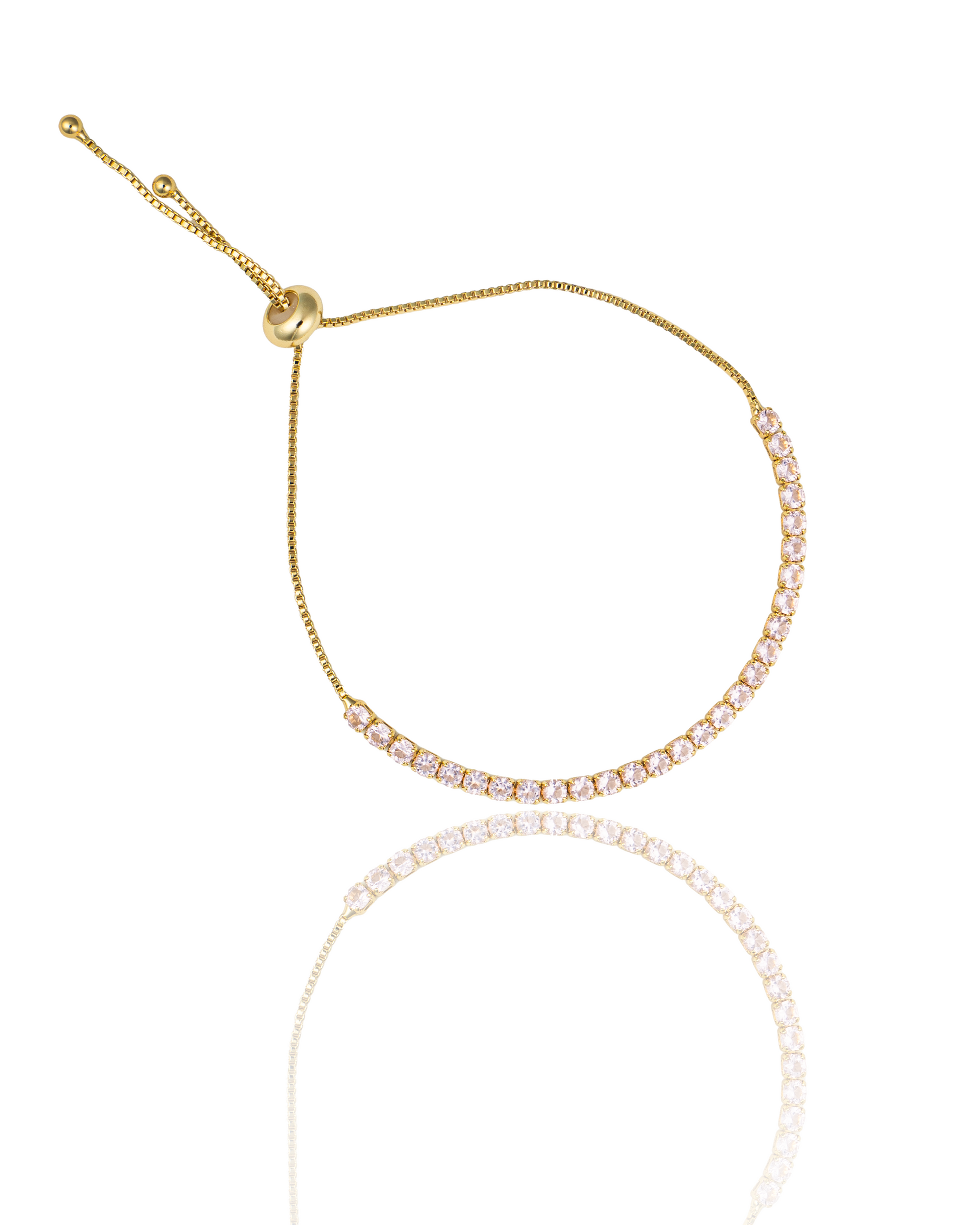 A gold tennis bracelet with sparkling cubic zirconia stones features an adjustable slider chain against a white background.