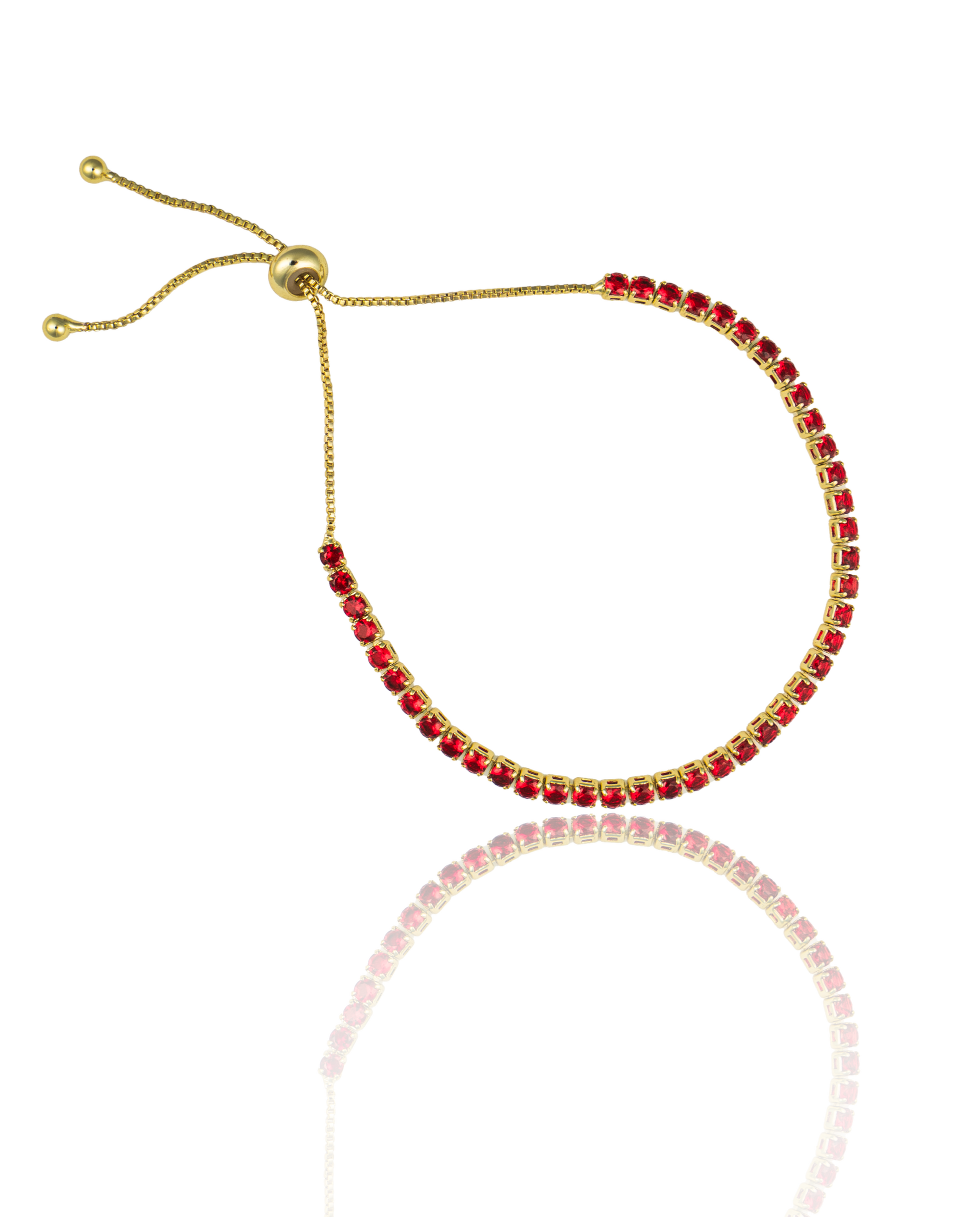 A gold bolo tennis bracelet features vibrant red square-cut gemstones and an adjustable sliding closure against a white background.