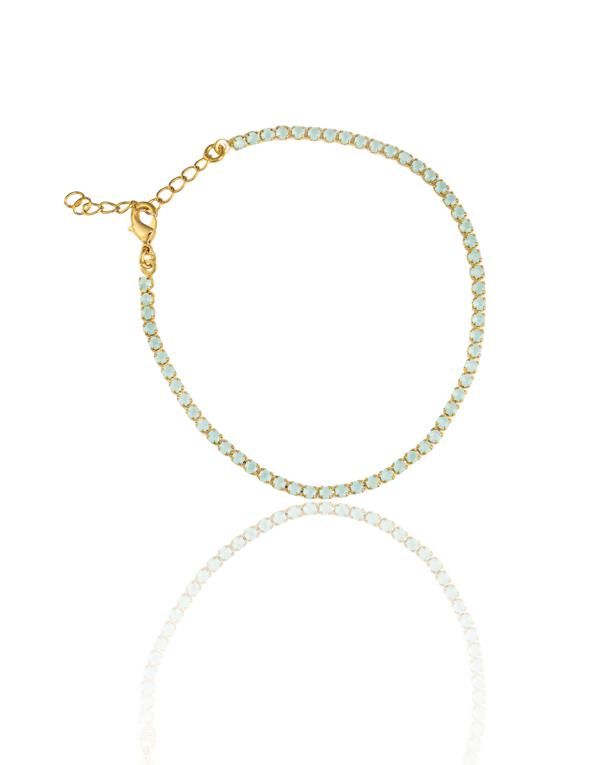 A delicate gold-plated tennis bracelet features round, light blue crystals and an adjustable chain clasp against a white background.