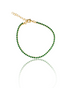 A gold tennis bracelet featuring vibrant green cubic zirconia stones rests on a reflective white surface.