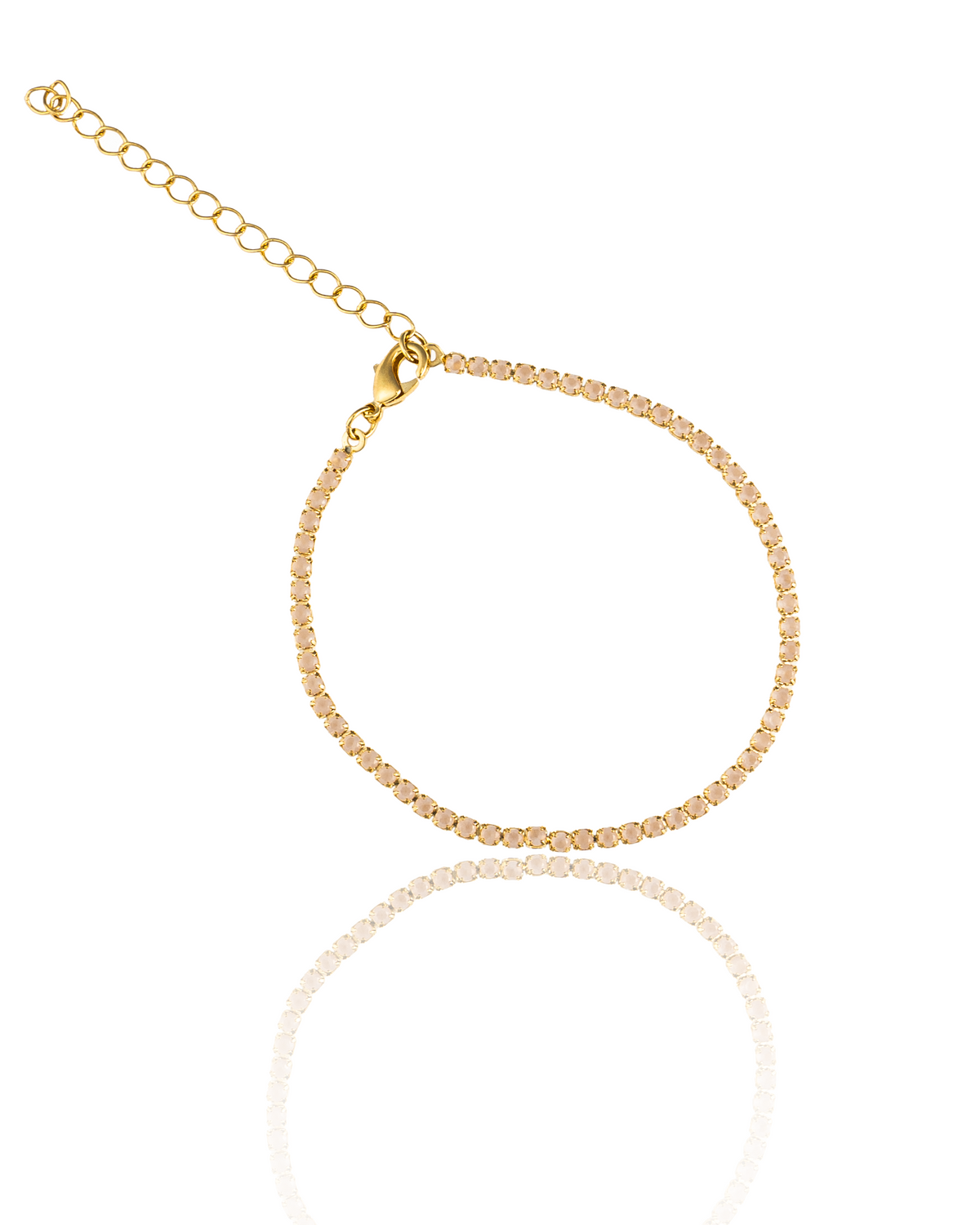 A delicate gold tennis bracelet features sparkling pink crystals and an adjustable extension chain against a clean white background.