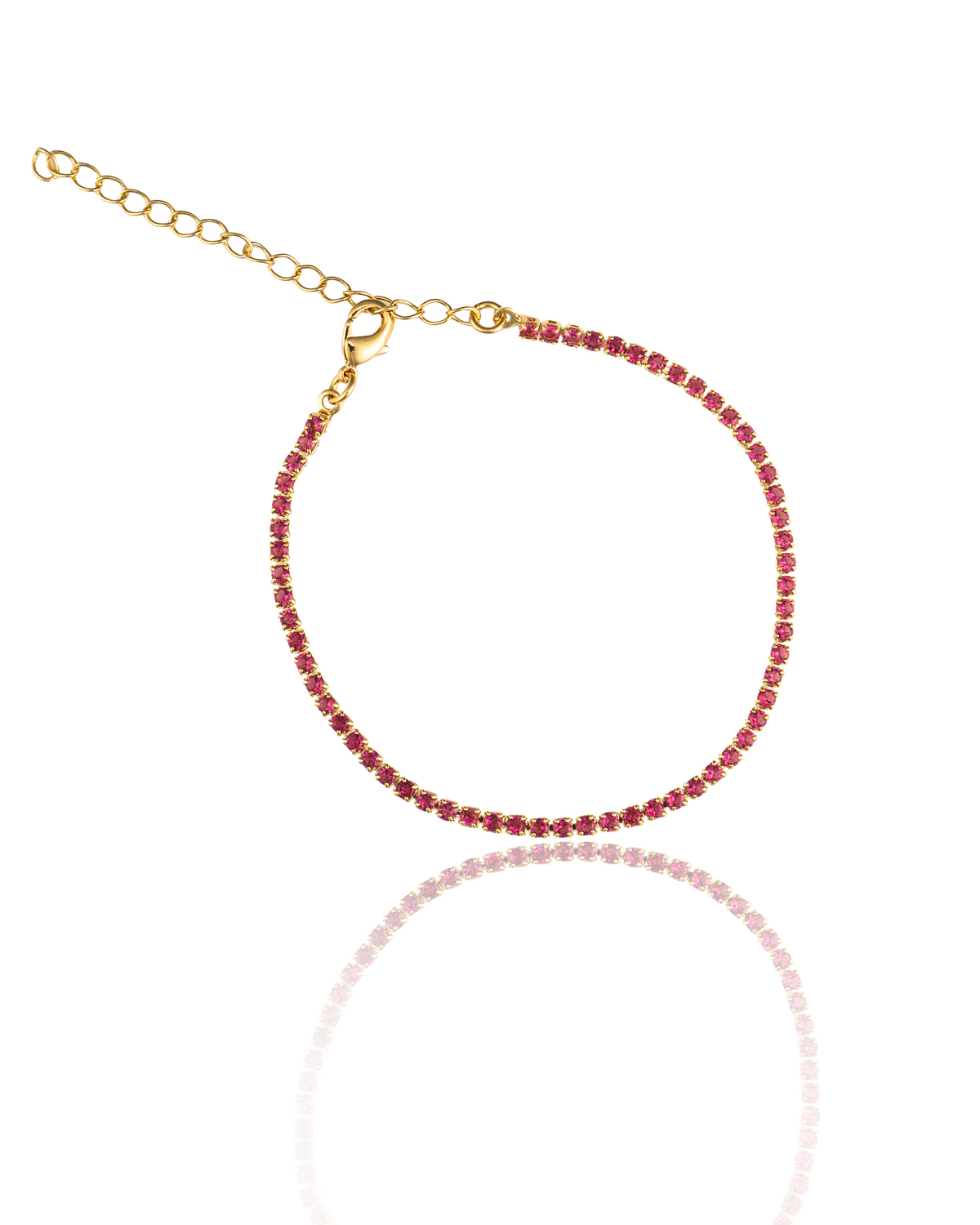 A delicate gold tennis bracelet sparkles with vibrant pink rhinestones against a clean white background.