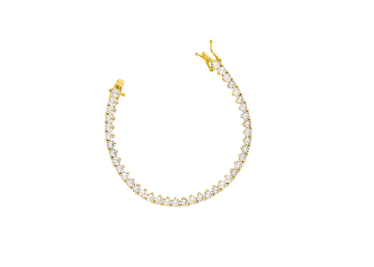 A sparkling gold tennis bracelet curves against a clean white background, showcasing a continuous line of brilliant cubic zirconia stones and a secure clasp.