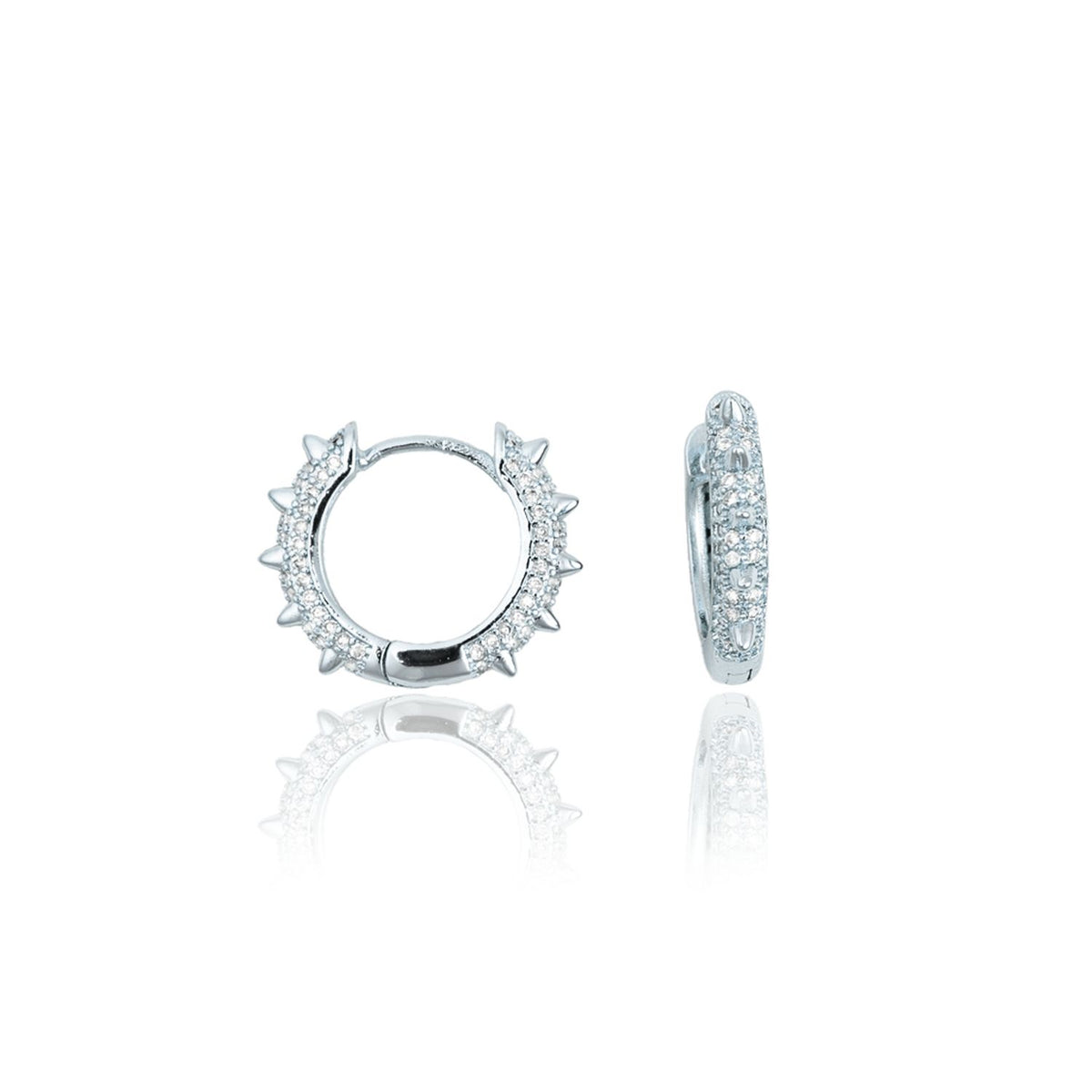 A pair of silver huggie hoop earrings featuring pavé-set stones and edgy spikes displayed on a reflective white surface.