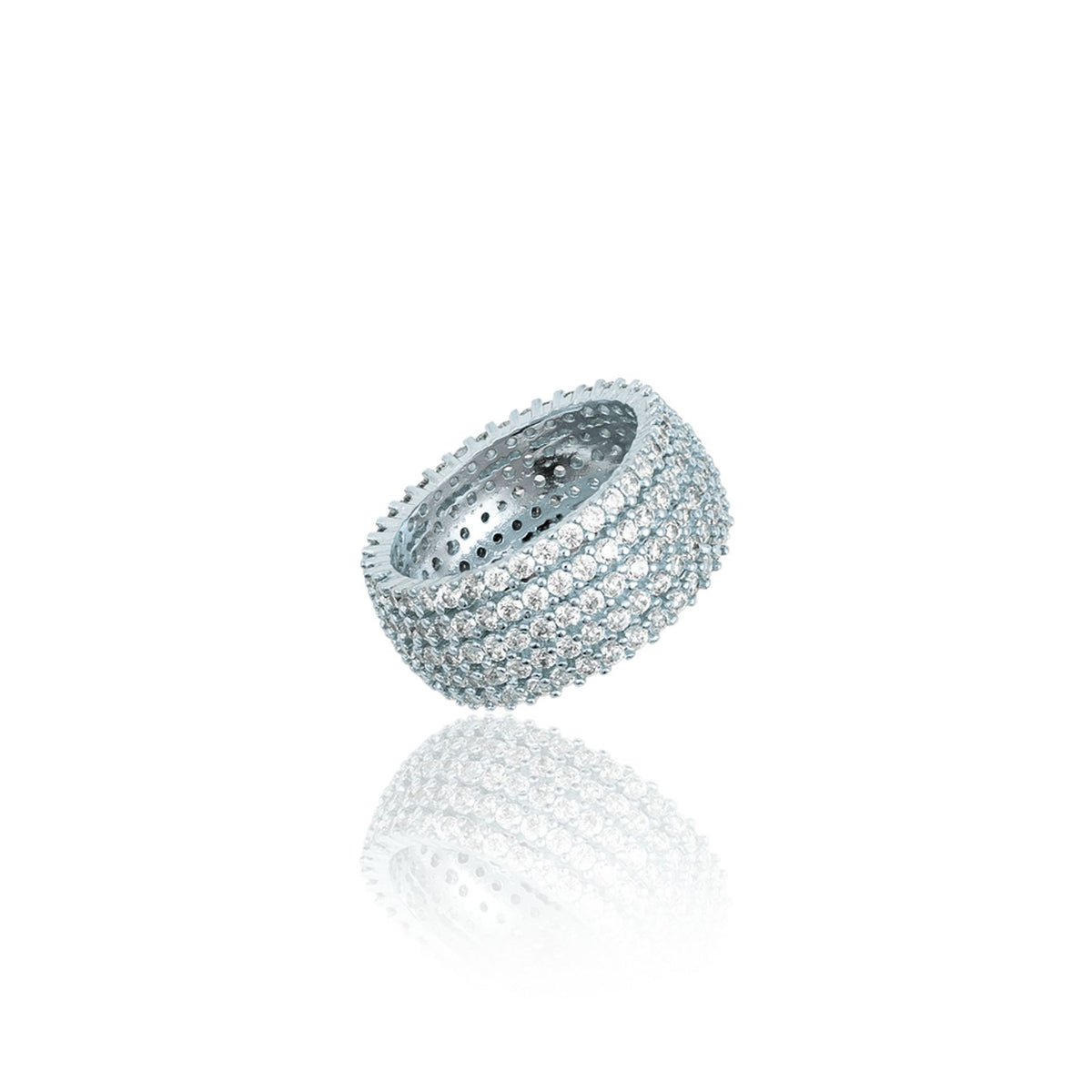 A wide silver pave ring encrusted with sparkling diamonds sits on a white surface, casting a clear reflection.