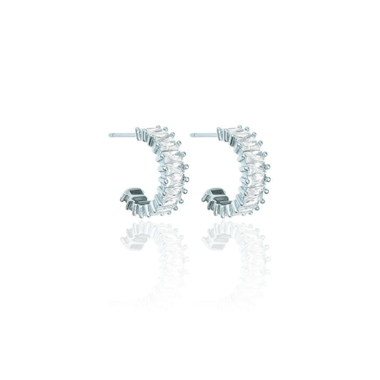 A pair of silver hoop earrings sparkle with baguette-cut crystals against a white background.