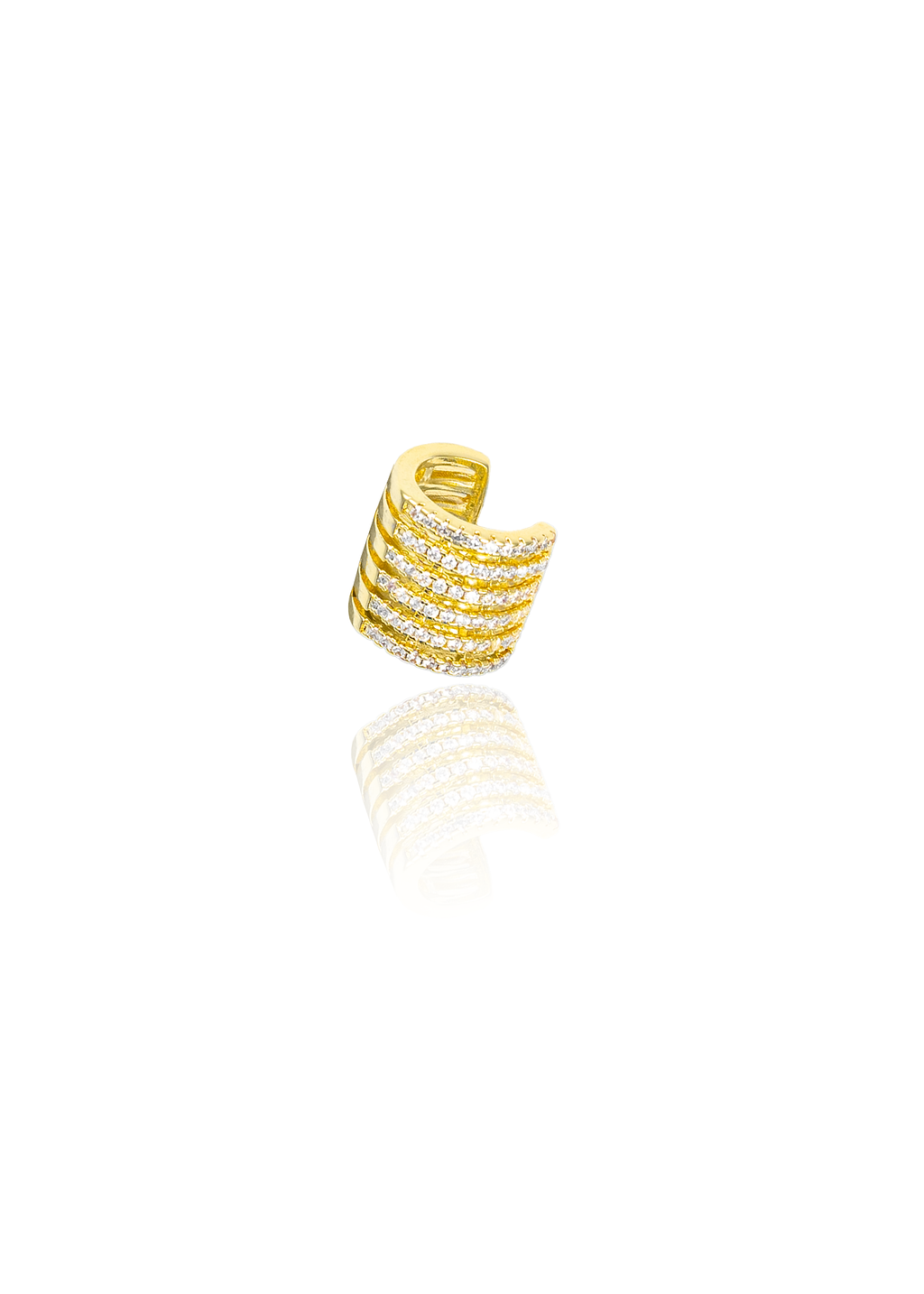 A shiny gold ear cuff encrusted with sparkling cubic zirconia stones rests against a clean white background with its reflection visible below.
