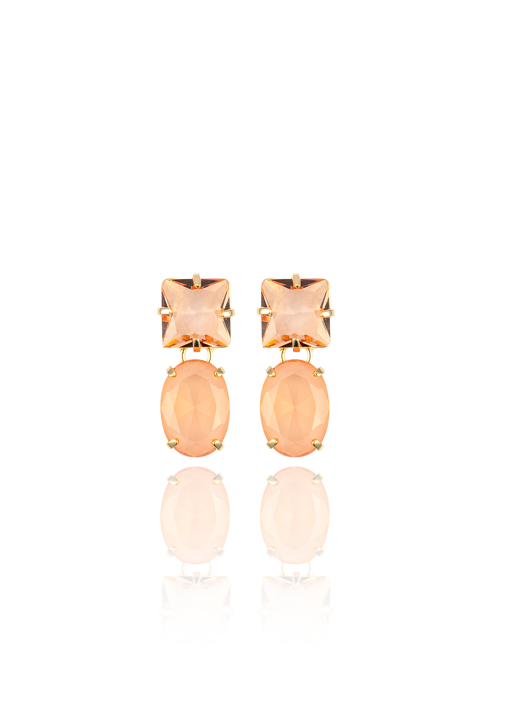 A pair of elegant gold-plated drop earrings featuring peach-colored square and oval crystals rests against a clean white background.