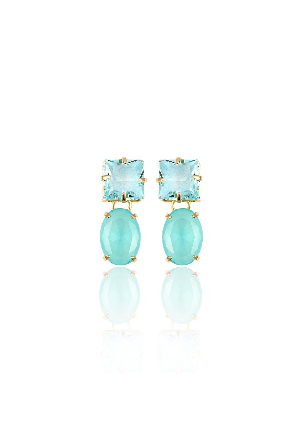 A pair of gold earrings featuring faceted square and oval aquamarine stones rest against a white background with a soft reflection.