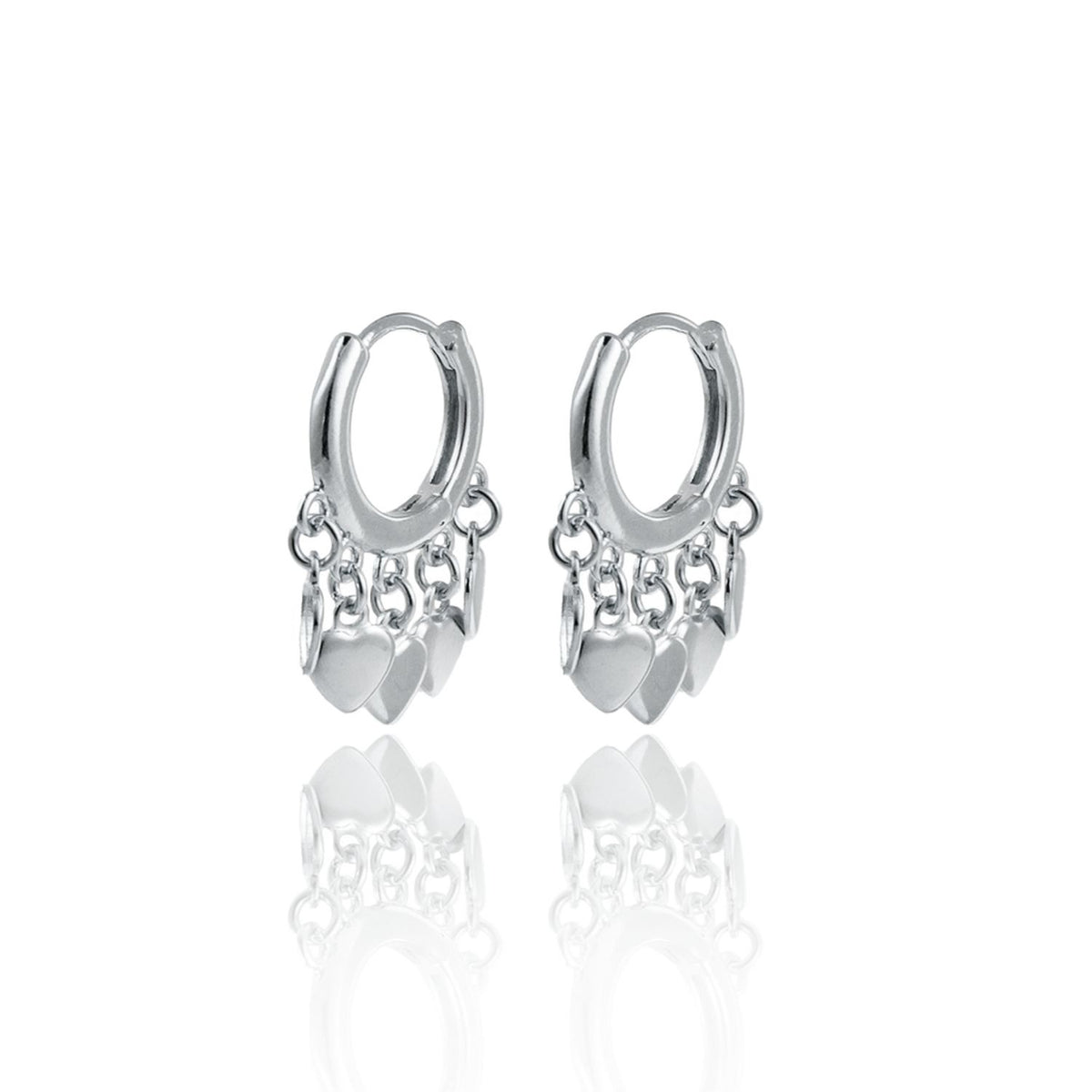 A pair of silver hoop earrings adorned with dangling heart charms and delicate chains rests on a reflective white surface.