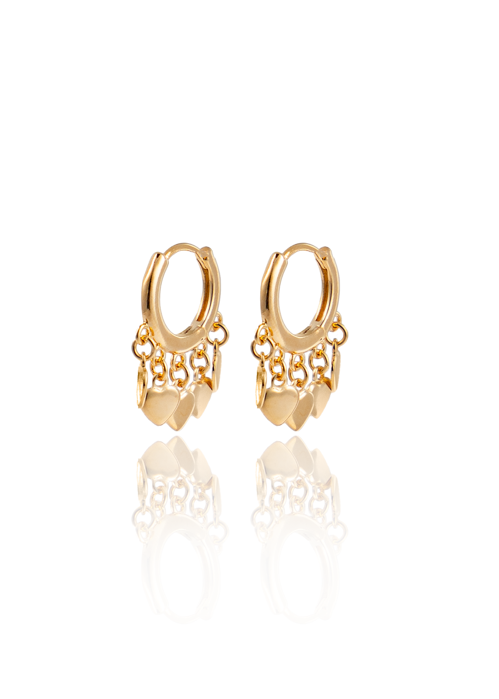 A pair of gold huggie hoop earrings dangle charmingly, featuring delicate charms shaped like little hearts on tiny chains.