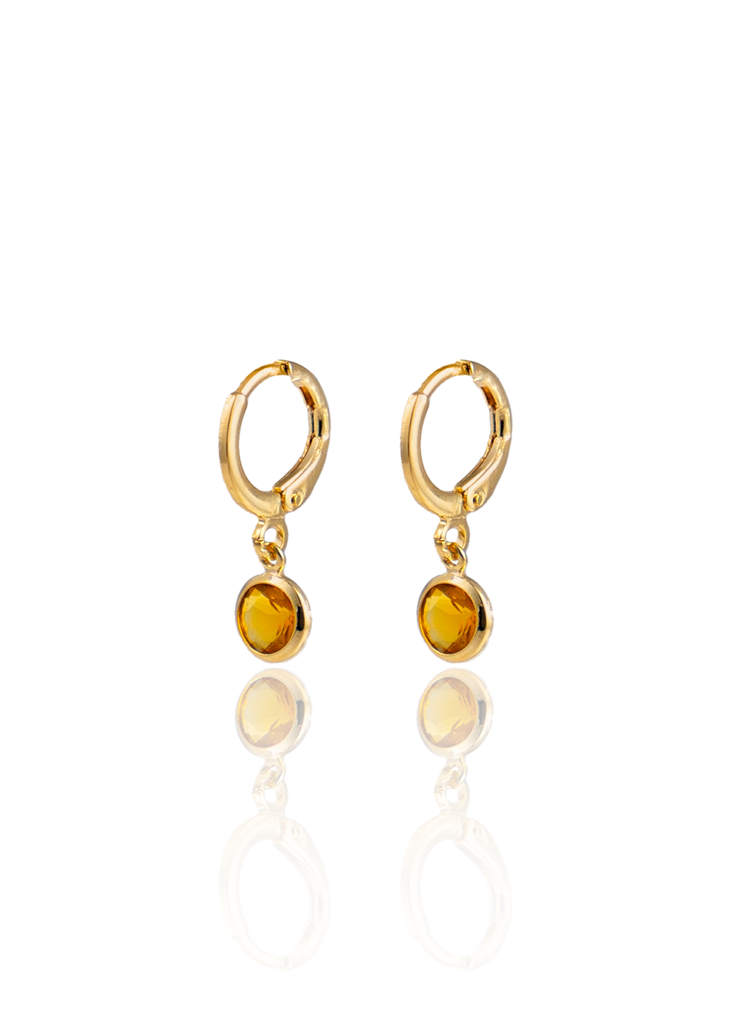 A pair of gold huggie hoop earrings featuring dangling round amber crystals is displayed against a white background.