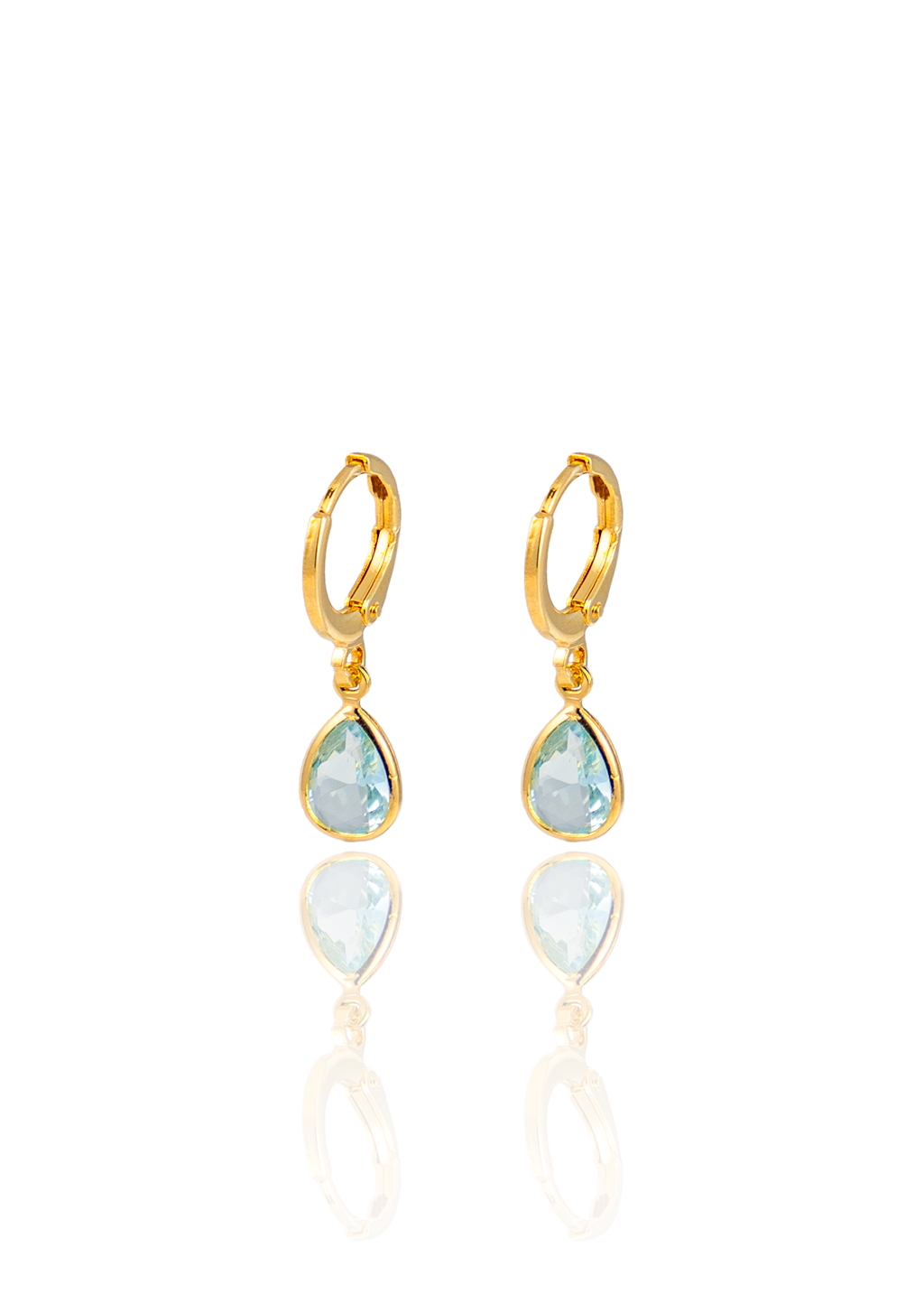 A pair of gold huggie hoop earrings featuring dangling, teardrop-shaped light blue gemstones against a white reflective background.