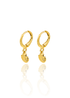 A pair of polished gold hoop earrings featuring dangling seashell charms gleams against a white background with a soft reflection below.