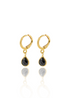 A pair of gold hoop earrings with dangling black teardrop gems gleams against a white background with a soft reflection below.