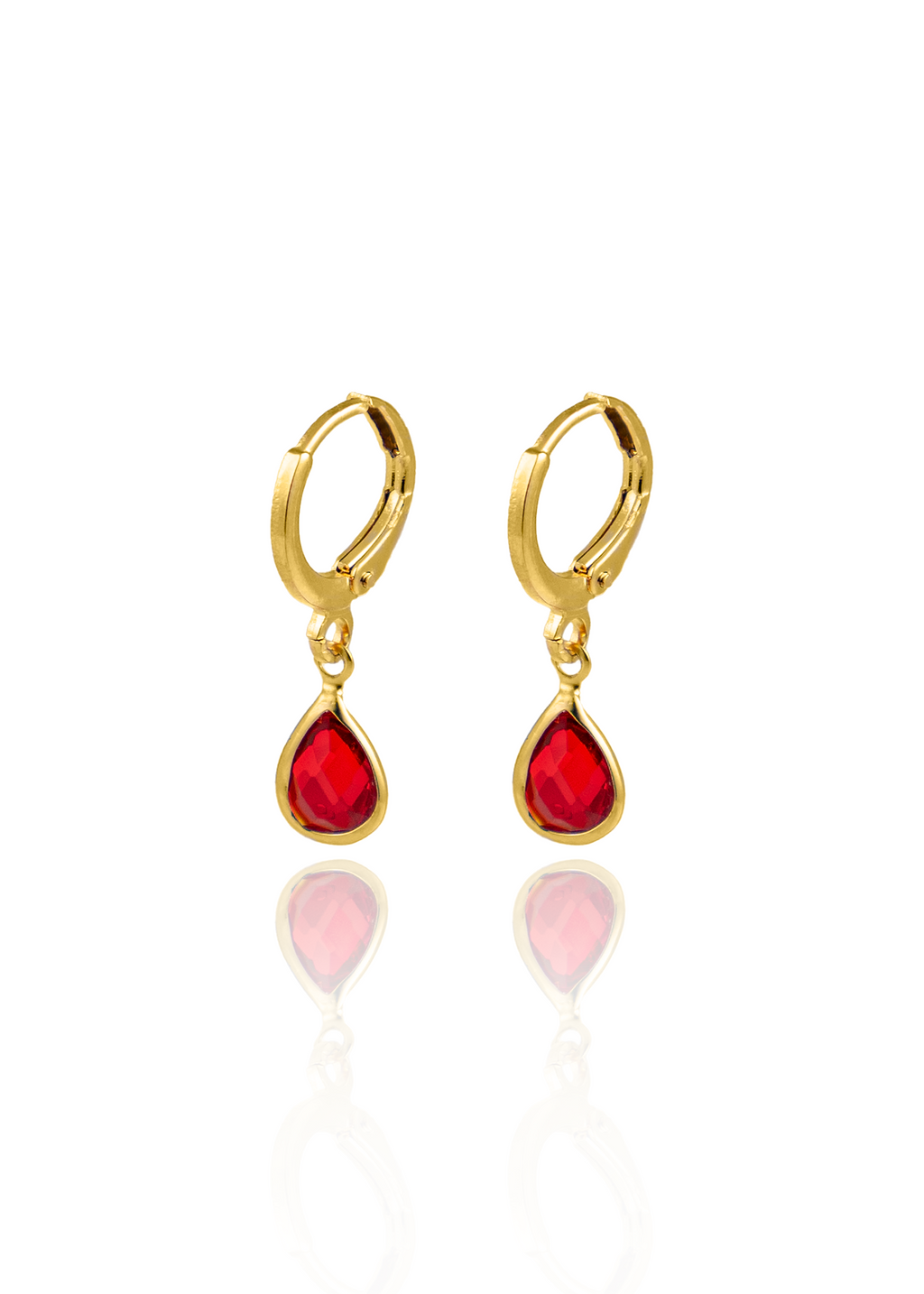A pair of elegant gold hoop earrings featuring vibrant red teardrop gemstone pendants hangs against a clean white background.