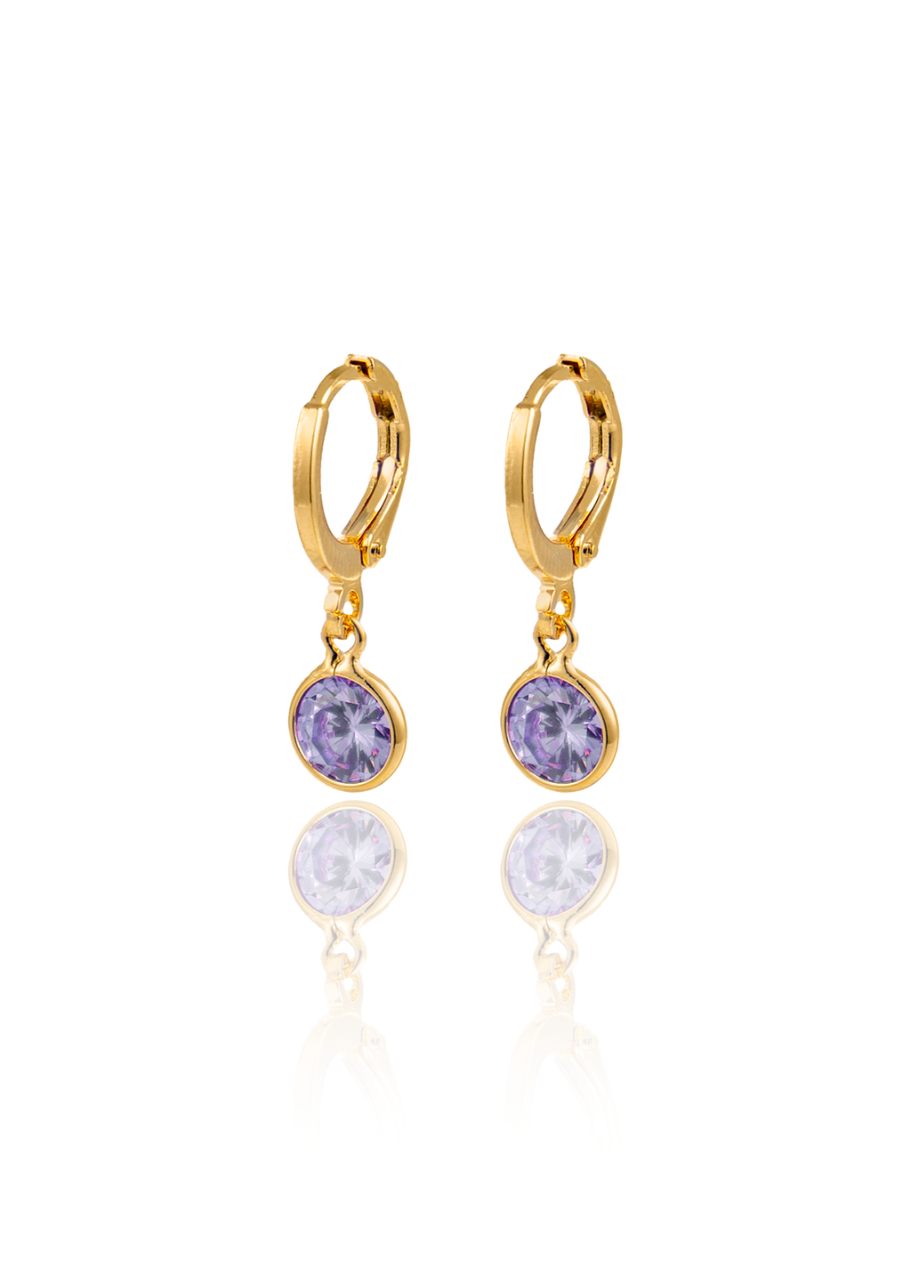 A pair of elegant gold huggie hoop earrings features dangling round purple gemstone charms reflecting on a white surface.