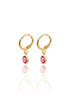 Two gold huggie hoop earrings dangle vibrant pink gemstone charms against a clean white background.