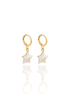A pair of gold huggie hoop earrings features hanging mother-of-pearl star charms against a clean white background.