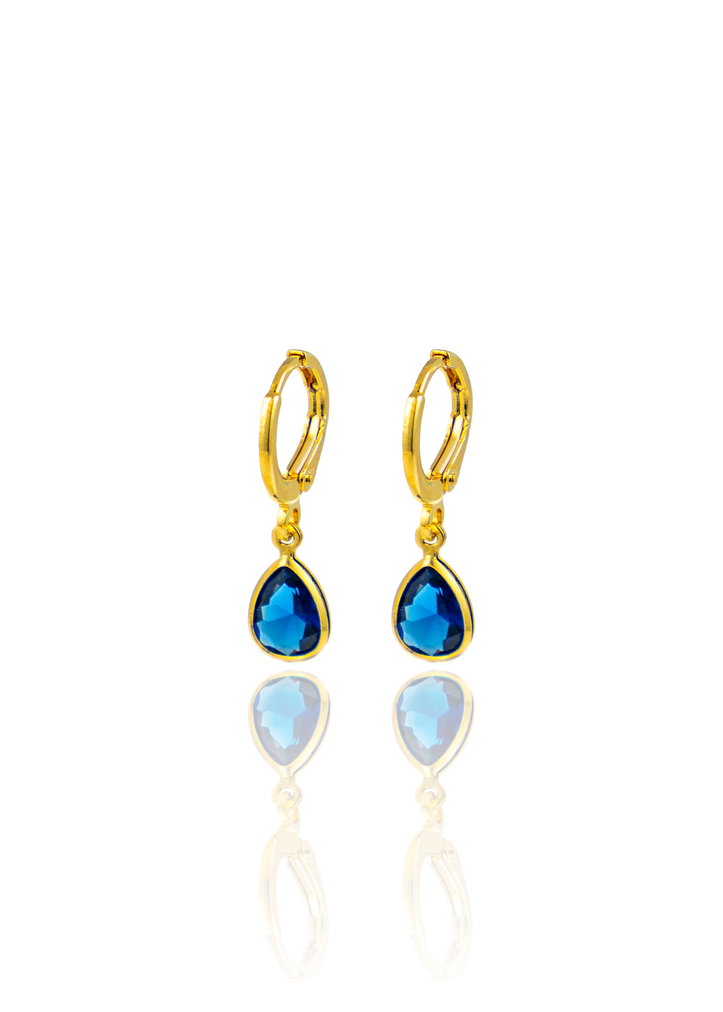 A pair of gold huggie hoop earrings features hanging teardrop-shaped blue sapphire gemstones against a clean white background.