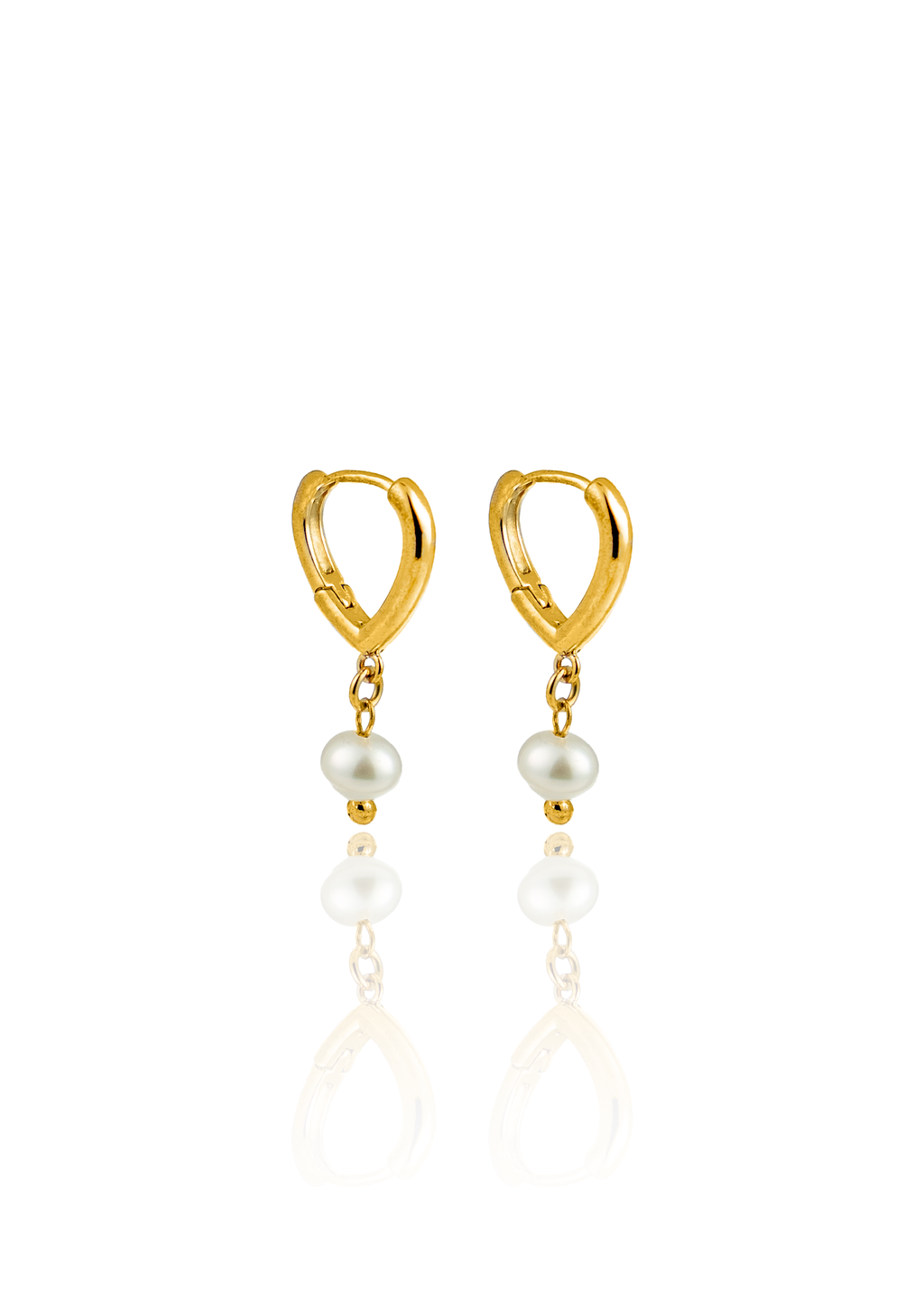 A pair of gold huggie hoop earrings featuring dangling freshwater pearls rests on a reflective white surface.