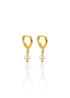 A pair of gold huggie hoop earrings featuring dangling freshwater pearls rests on a reflective white surface.