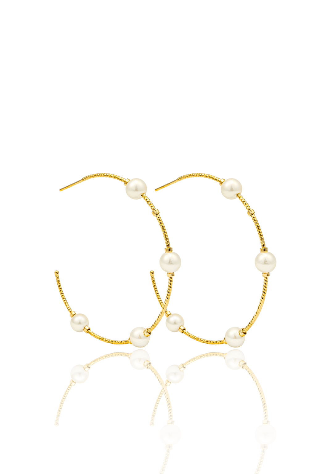 A pair of elegant gold hoop earrings embellished with pearls rests on a reflective white surface.