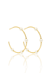 A pair of elegant gold hoop earrings embellished with pearls rests on a reflective white surface.