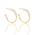 A pair of elegant gold hoop earrings embellished with ascending white pearls sits against a clean white background, reflecting softly on the glossy surface below.