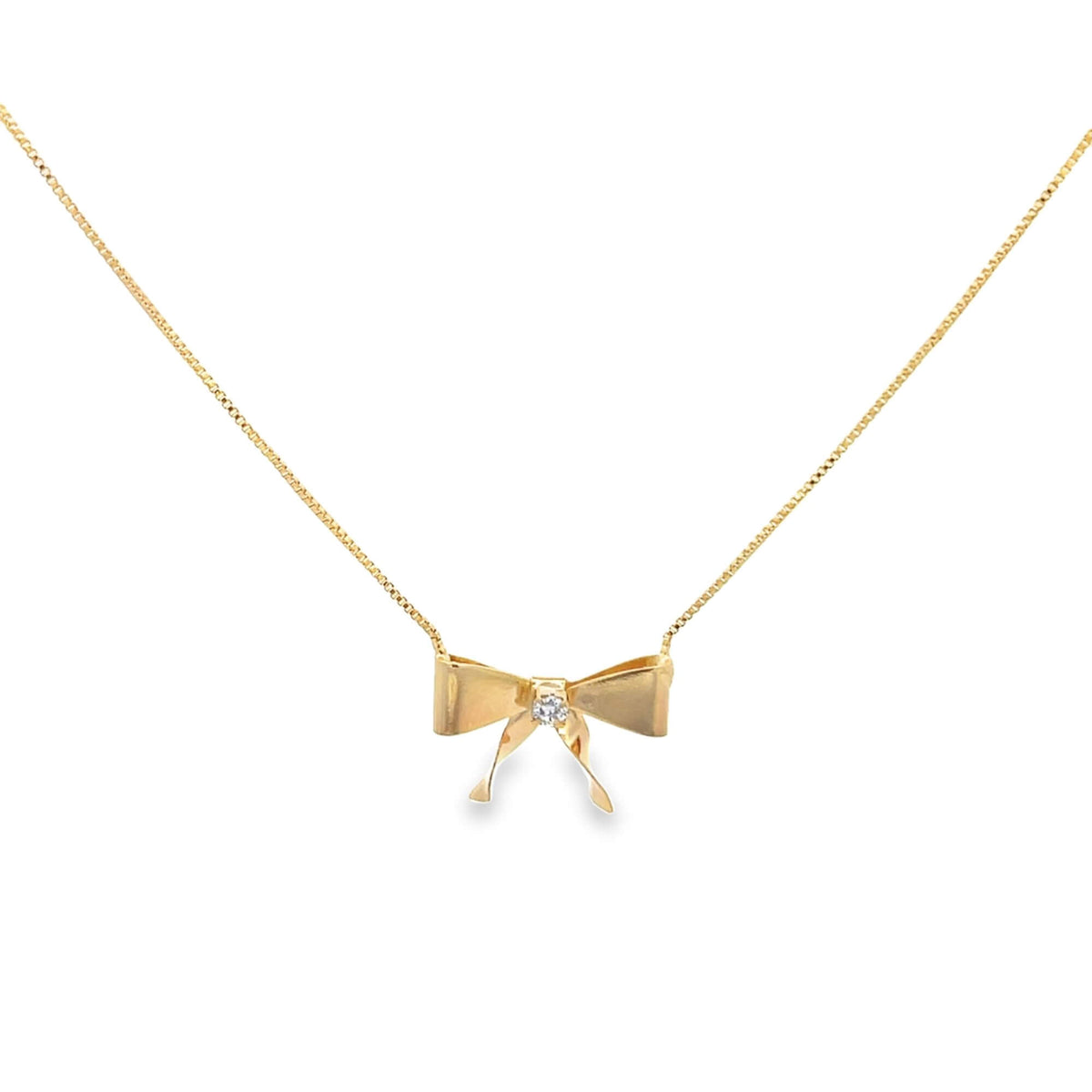 A delicate gold bow pendant necklace featuring a sparkling center diamond hangs against a clean white background.