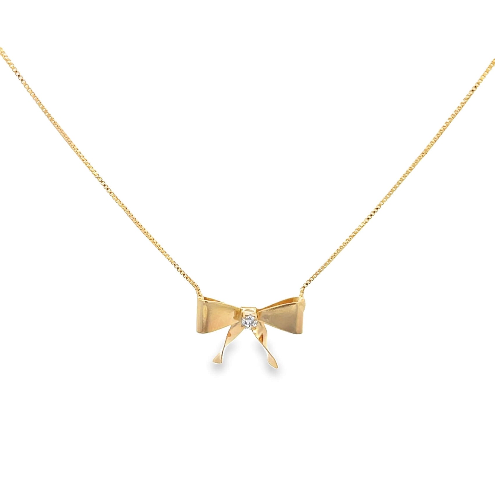 A delicate gold bow pendant necklace featuring a sparkling center diamond hangs against a clean white background.