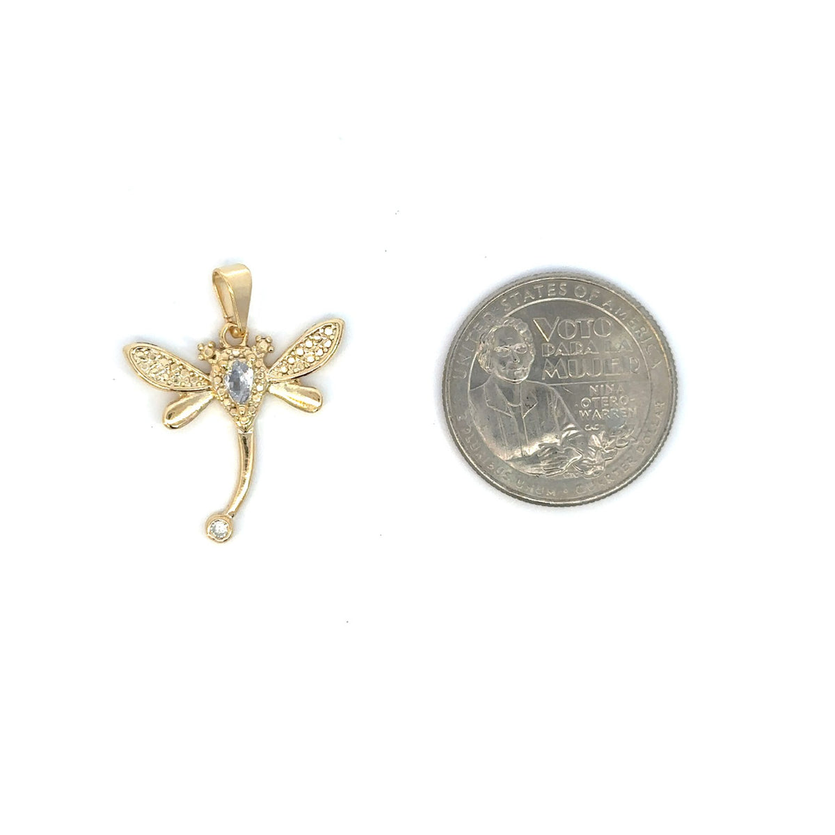 A gold dragonfly pendant with sparkling cubic zirconia stones rests next to a US quarter for size comparison on a white background.