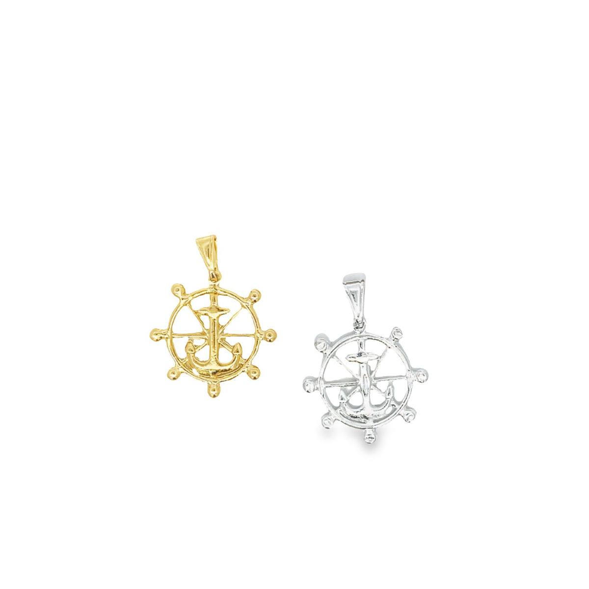 A gold and a silver ship wheel pendant with an anchor design rest side by side against a white background.