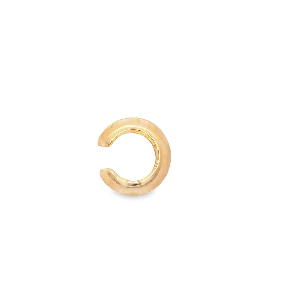 A minimalist gold ear cuff rests against a clean white background.