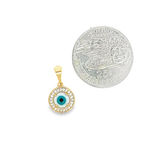 A gold evil eye pendant featuring sparkling cubic zirconia stones rests next to a US quarter coin for scale.