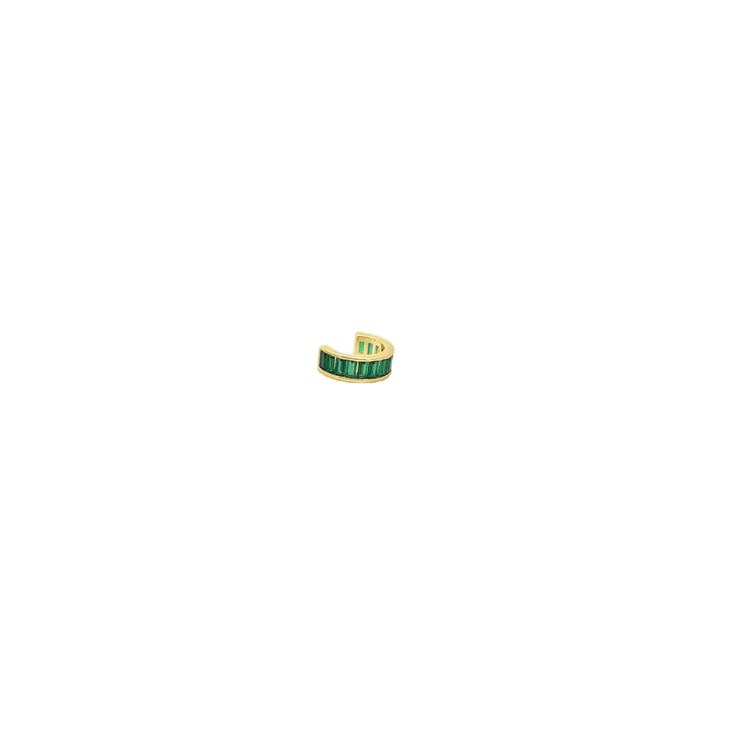 A gold ear cuff featuring vibrant green baguette-cut stones rests against a clean white background.