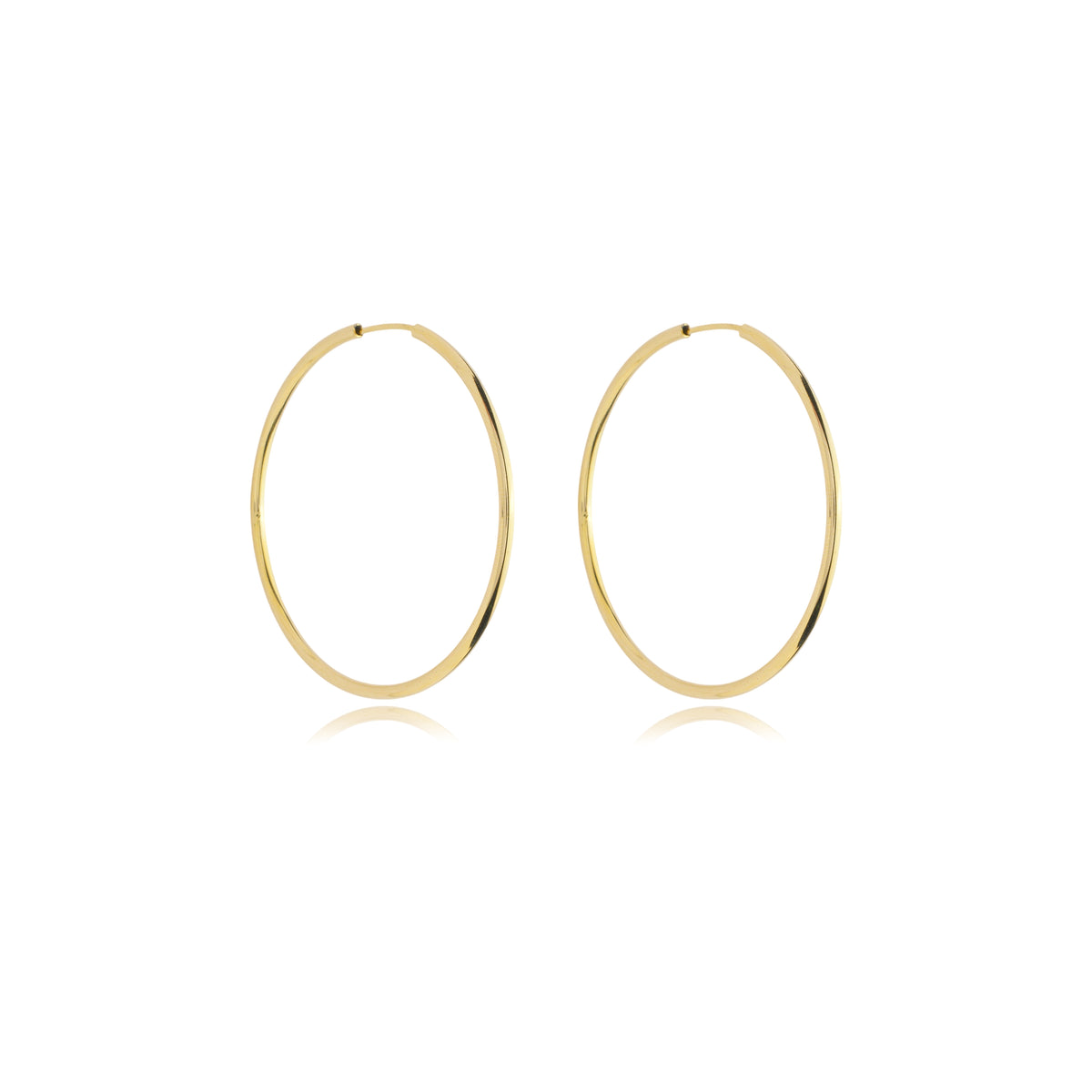 A pair of minimalist gold hoop earrings gleams against a clean white background.