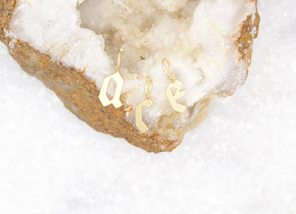 Three delicate gold initial charms spelling ACE rest inside a sparkling white geode crystal.