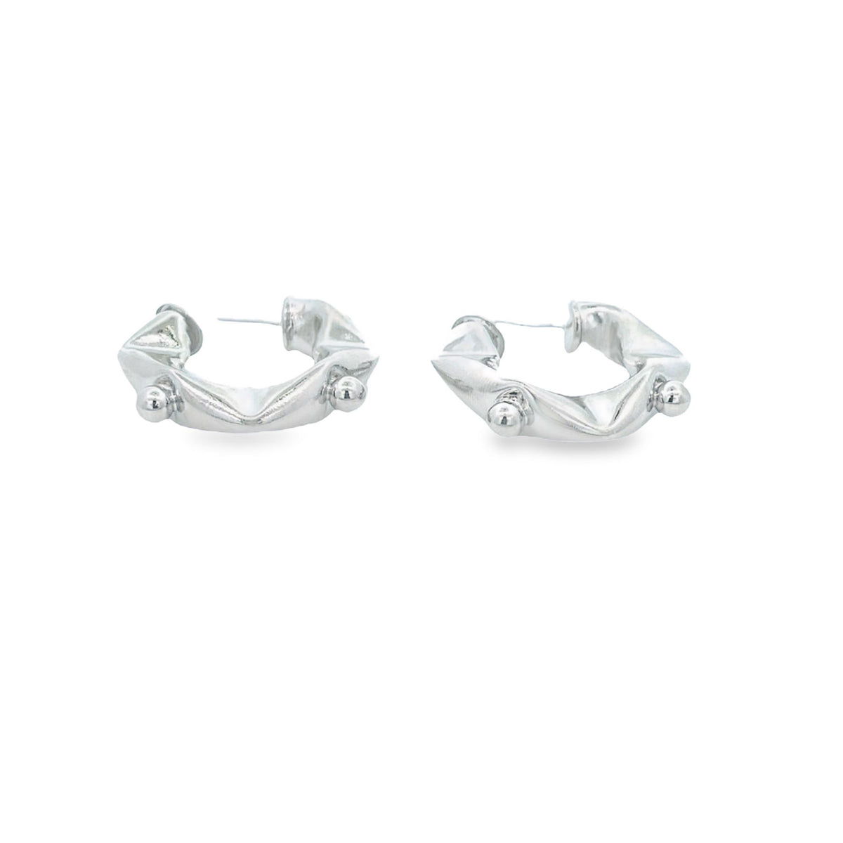 A pair of chunky silver hoop earrings features a textured design with small spherical accents against a clean white background.